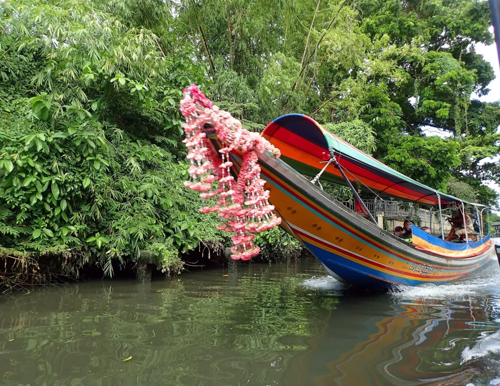 Farbiges Longtail-Boot mit Bugbändern in einem Khlong von Bangkok – Foto: Gozitano