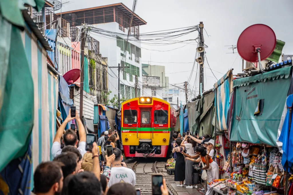 Regionalzug fährt durch den Maeklong Railway Market zwischen Marktständen – Foto: Takeshi Aida