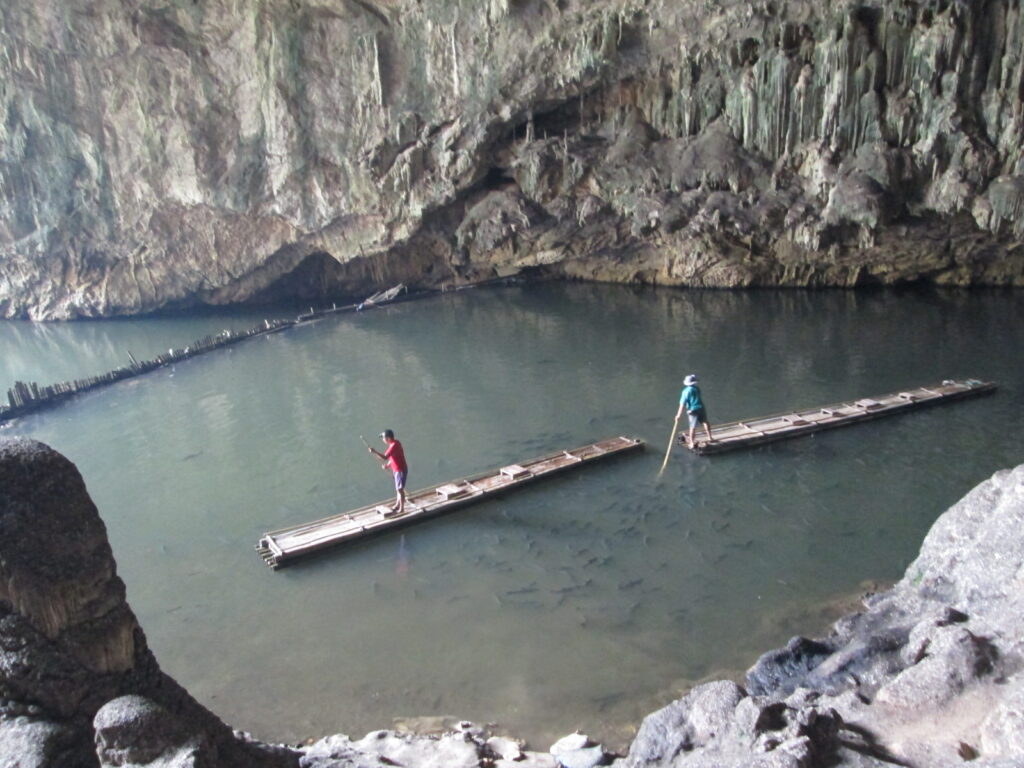 Bambusflöße im beleuchteten Flussgang der Tham-Lod-Höhle